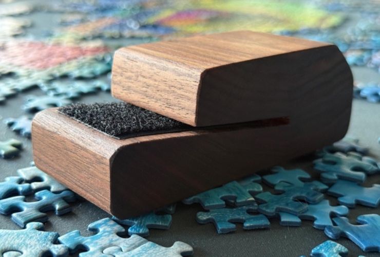 Angle photo of a puzzle box top holder set on top of colorful puzzle pieces.